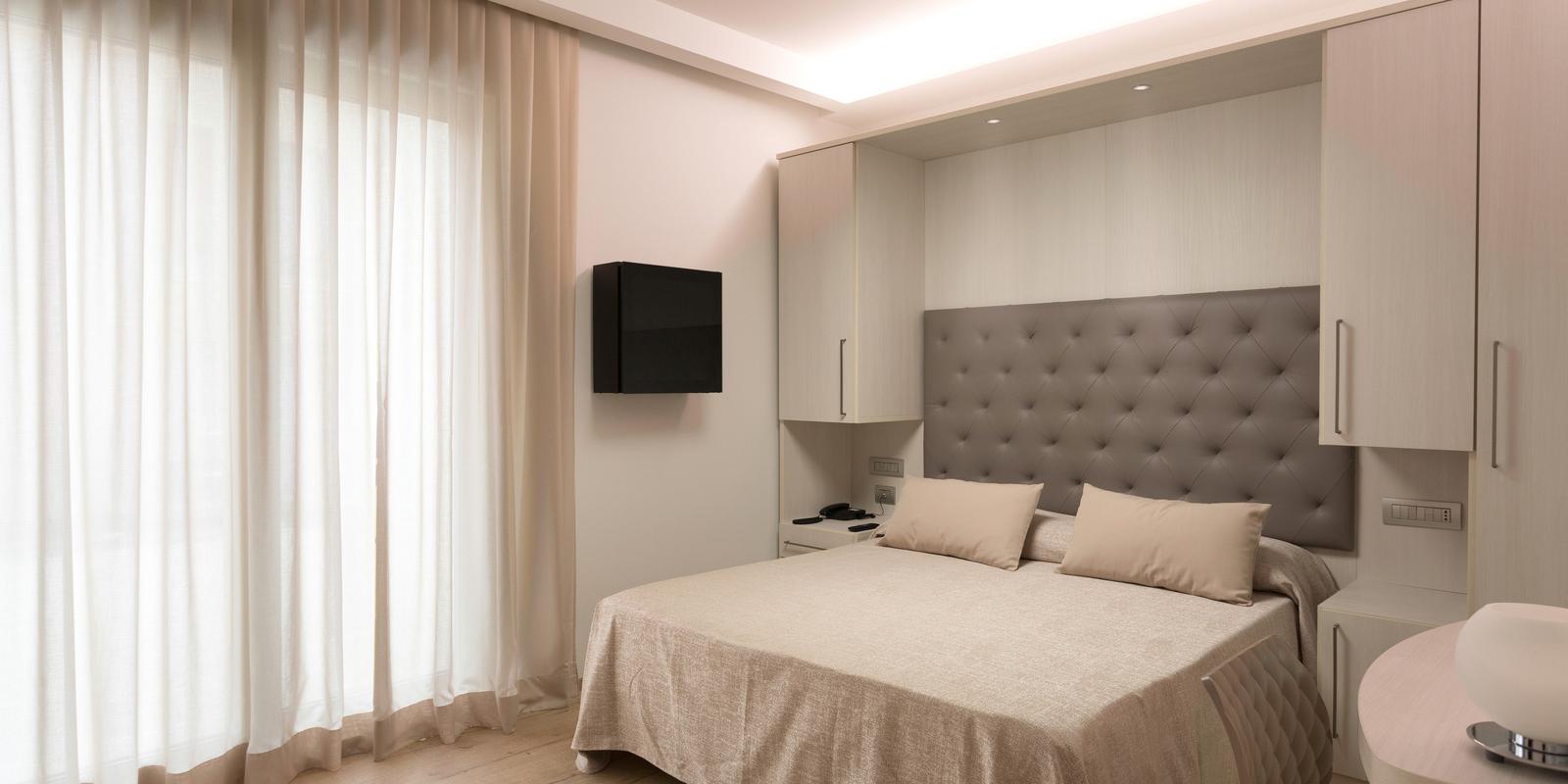 Camera da letto moderna con letto matrimoniale e tende chiare.