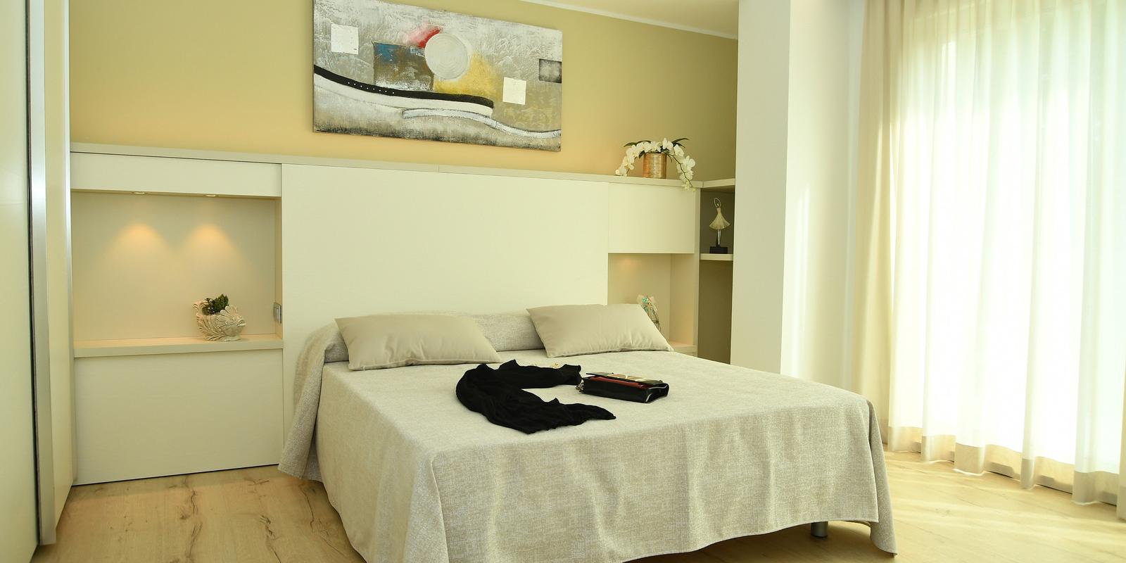 Camera moderna con letto, quadro astratto e scarpe rosse.