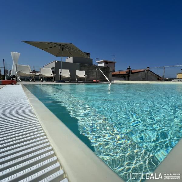 Piscina sul tetto con sedie a sdraio e ombrellone.